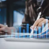 Dłoń z rysikiem na tablecie, na którym wyświetlane są wykresy i procenty. To pokazuje, co to znaczy digital – analizę danych i wzrost.