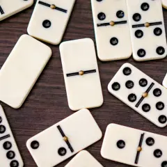 Rozrzucone kostki do gry w domino, w tym jedna kostka bez oczek, czekają na swoją kolej w grze.
