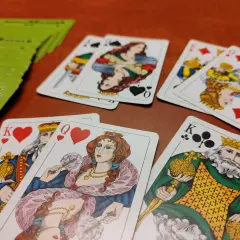 Króle i damy na kartach, stos zielonych kart w tle. Czas na grę w tysiąca zasady!