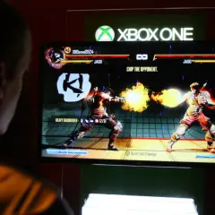 Gracz gra w bijatykę na Xbox One. To wersja cyfrowa gry, gdzie postać Jago strzela ogniem.