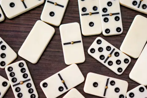 Rozrzucone kostki do gry w domino, w tym jedna kostka bez oczek, czekają na swoją kolej w grze.