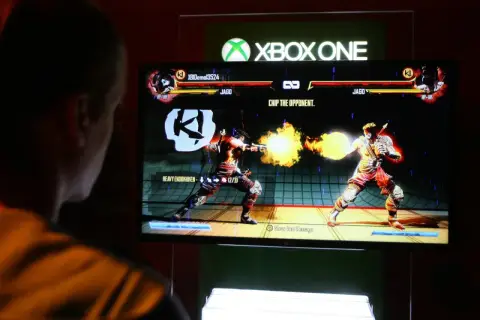 Gracz gra w bijatykę na Xbox One. To wersja cyfrowa gry, gdzie postać Jago strzela ogniem.