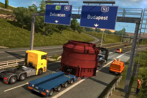 Transport ciężkiej maszyny w Euro Truck Simulator 3. Ciężarówka z żółtą kabiną i niebieską naczepą przewozi ogromny czerwony element.