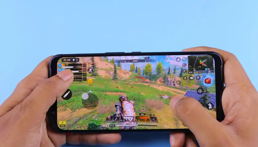 Ręce trzymają smartfon, na którym widać dynamiczną rozgrywkę z jednej z najlepszych gier android. Akcja toczy się w malowniczej, górskiej scenerii.