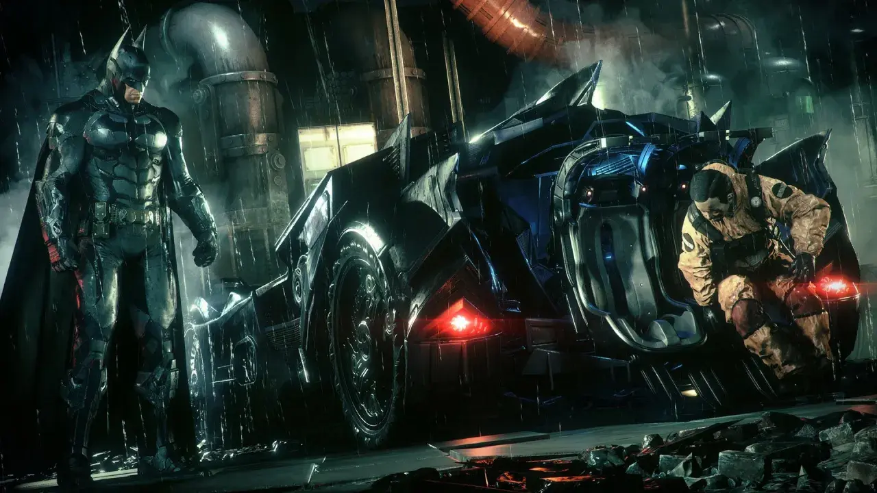 Batman w deszczu przy Batmobilu, gotowy do akcji w Arkham City. Obok niego klęczy mężczyzna w pomarańczowym kombinezonie.