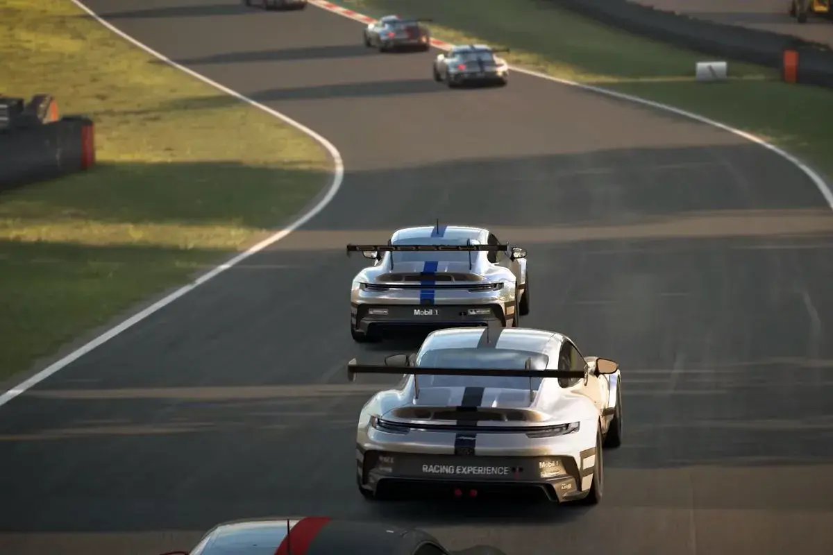 Wyścigowe Porsche na torze, w tle inne samochody. Emocje jak w Assetto Corsa Evo.