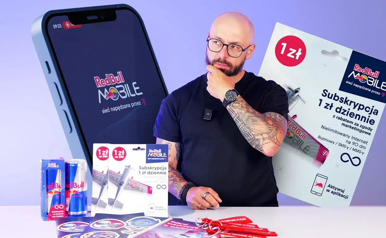 Mężczyzna z tatuażami zastanawia się nad ofertą Red Bull MOBILE. Na stole leżą puszki Red Bull, karty SIM i gadżety.