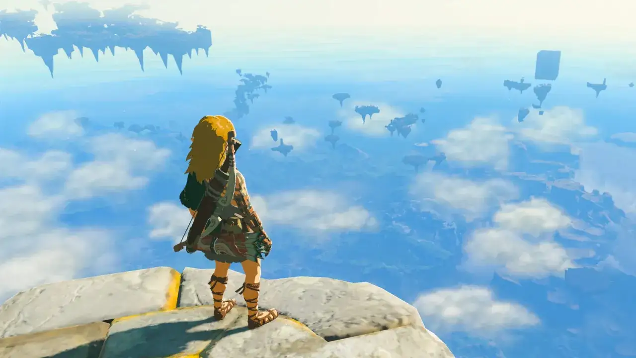 Link z gry Zelda: Tears of the Kingdom stoi na krawędzi skalnej wyspy, patrząc na unoszące się w powietrzu fragmenty lądu.