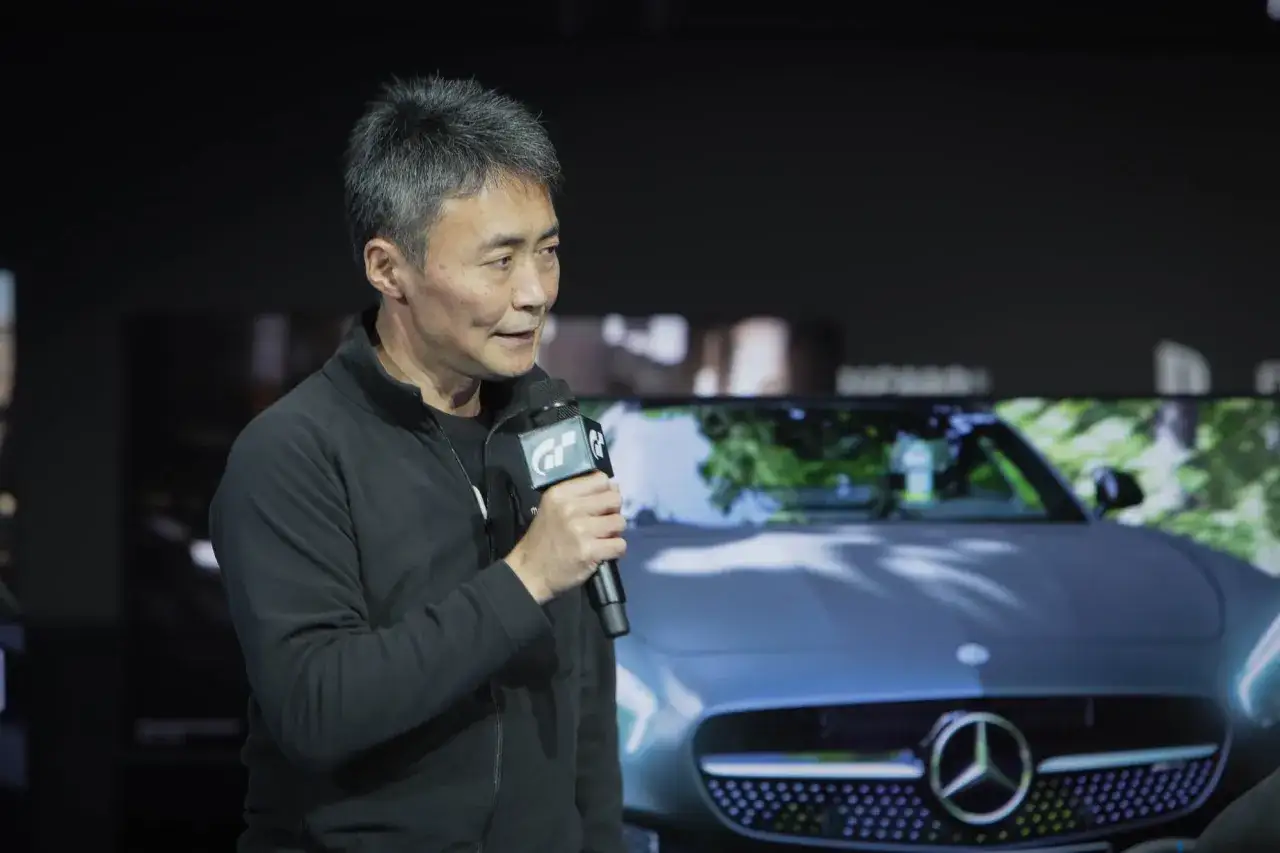Kazunori Yamauchi, twórca Gran Turismo, prezentuje nowości w grze Gran Turismo na PC, z Mercedesem w tle.